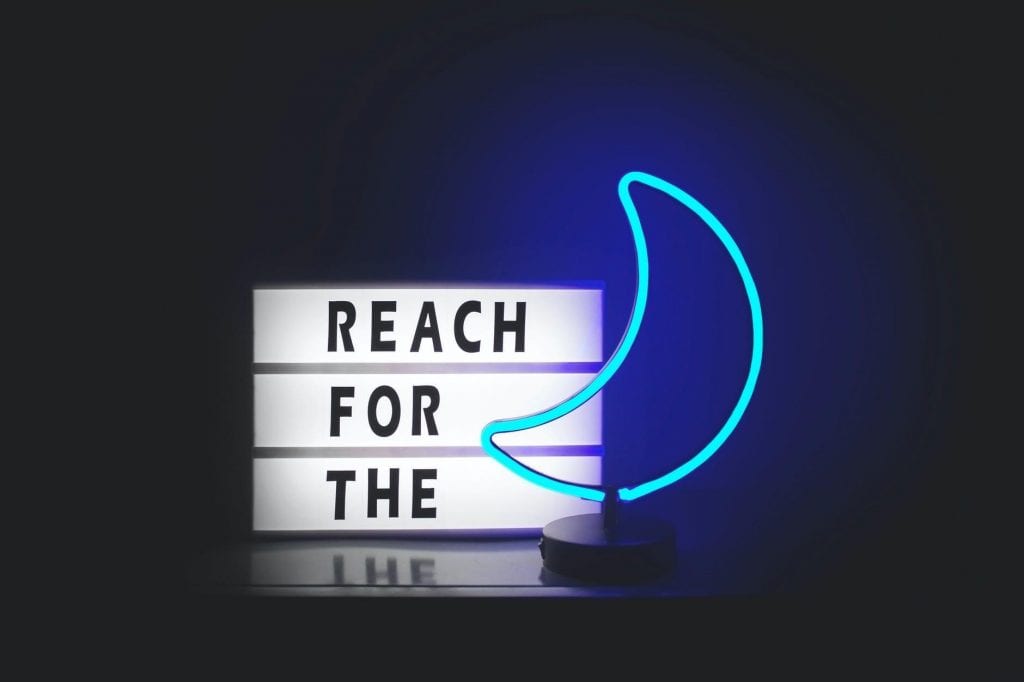 A blue neon sign in the shape of a moon that is a part of the quote.