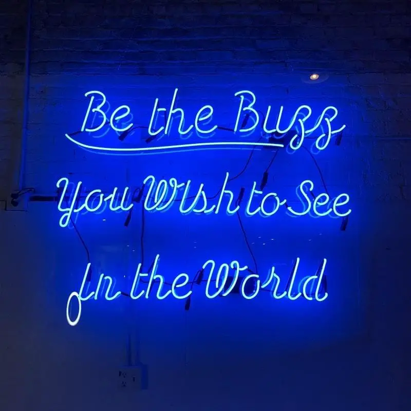 A blue neon sign with an inspirational quote.